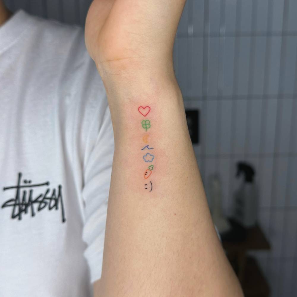 Hand poked style emojis tattoo placed on the wrist.