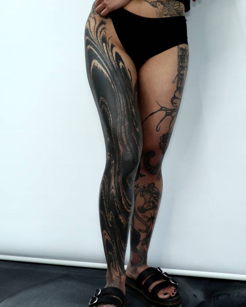 Abstract cover up leg sleeve tattoo in blackwork style.