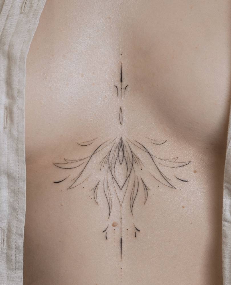 Line art style ornamental tattoo located on the sternum.