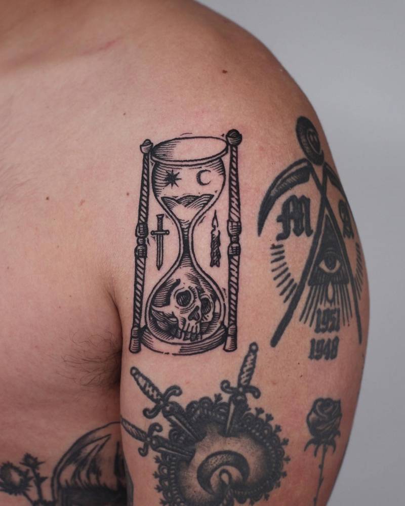 Engraving style hourglass tattoo located on the shoulder.