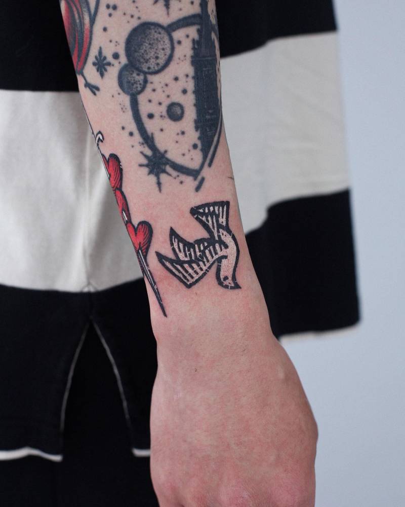 Dove tattoo located on the wrist, done in pop art style.