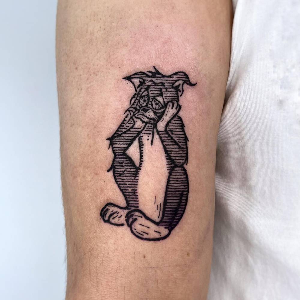 Sad Tom tattoo in engraving style located on the upper arm.