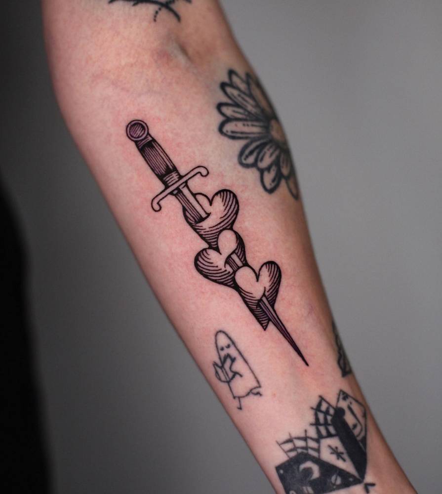 Hearts and dagger tattoo in engraving style done on the inner forearm.