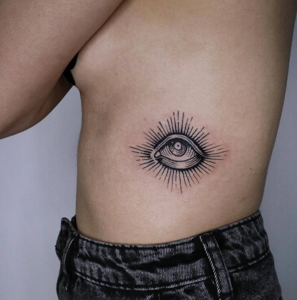 Engraving style eye tattoo placed on the rib.