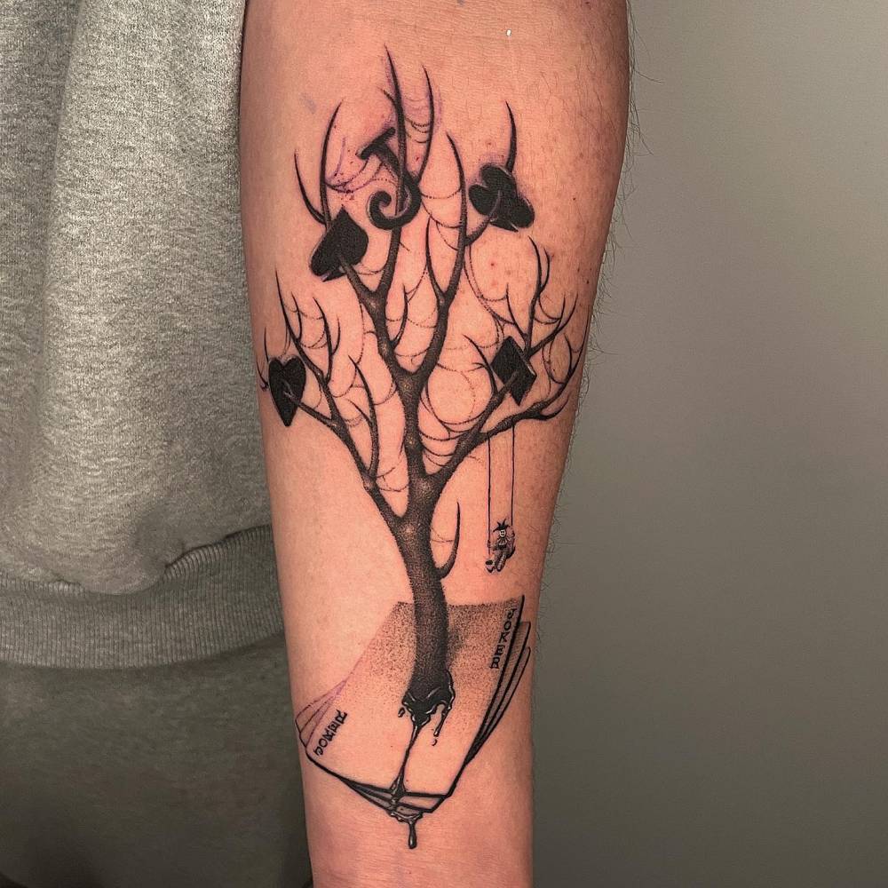 Joker Tree tattoo in dotwork style located on the inner forearm.
