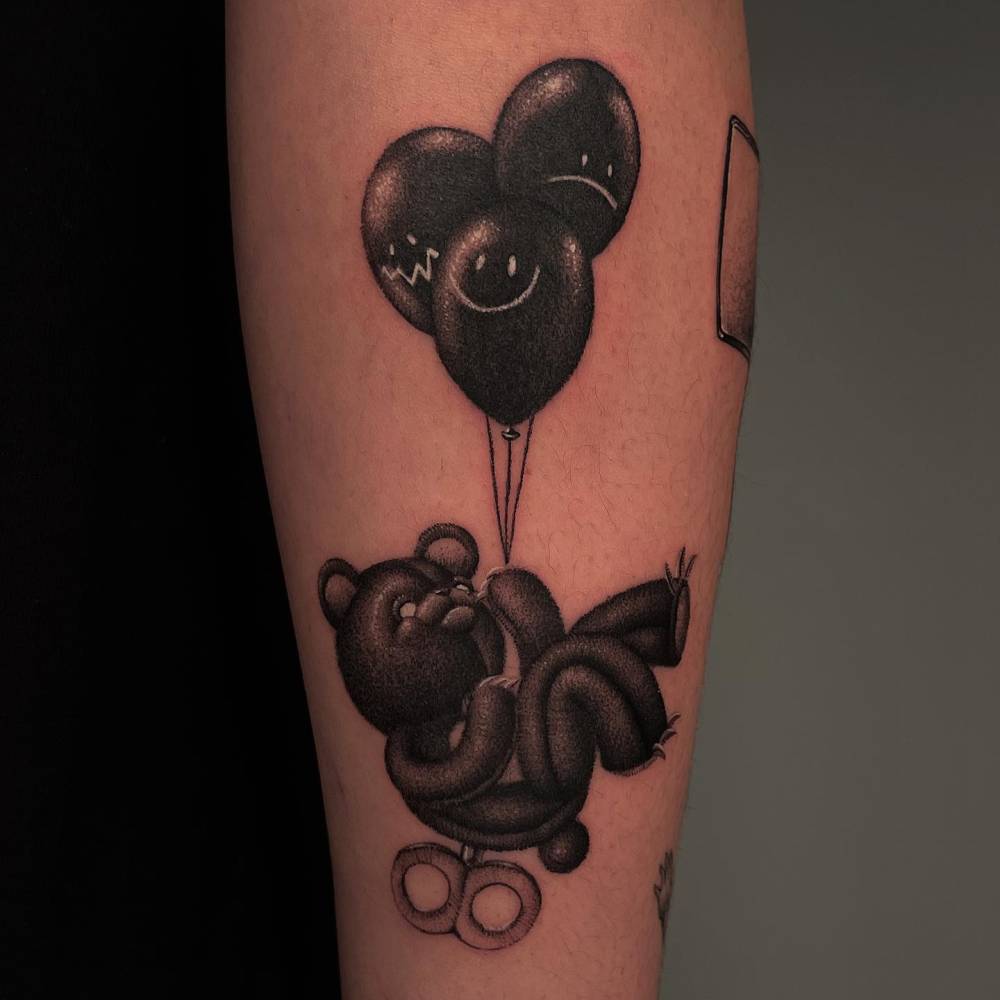 Teddy bear and balloons tattoo in dotwork style located on the inner forearm.