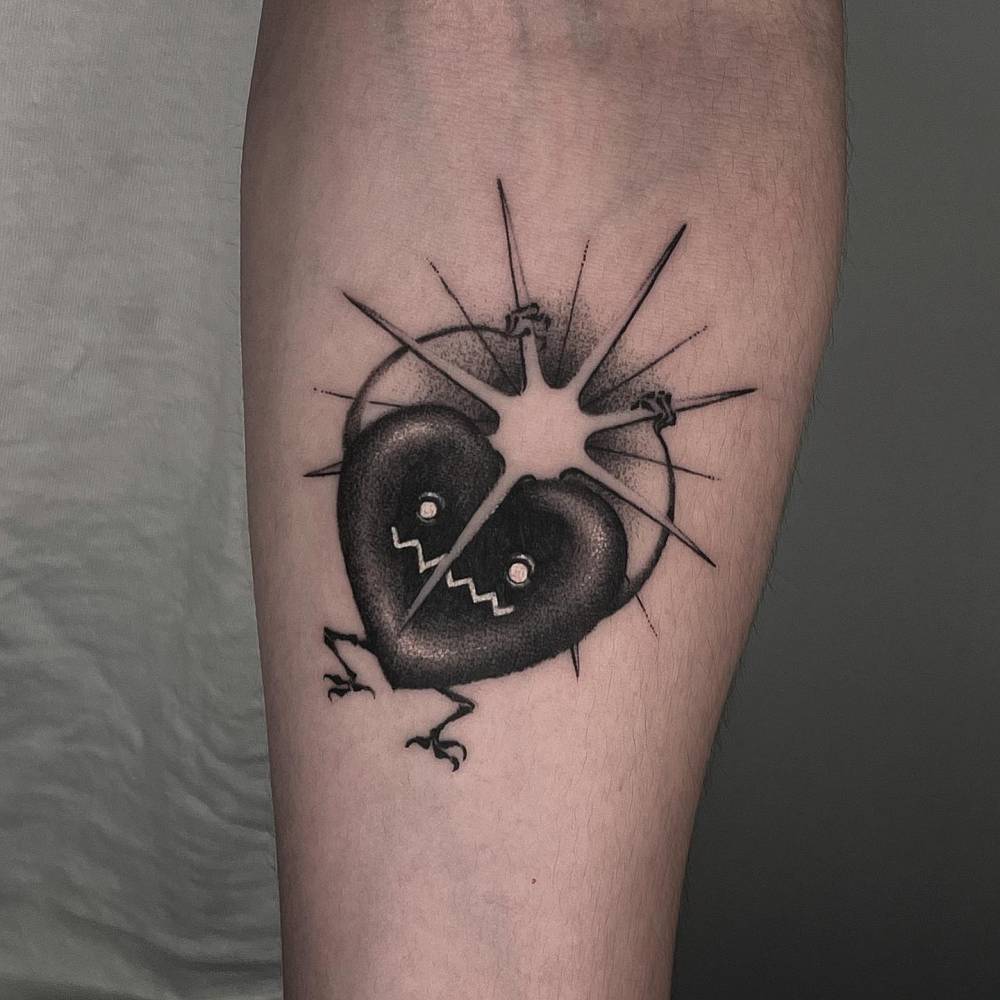 Cartoon style broken heart tattoo located on the inner forearm.