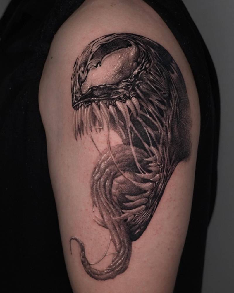 Venom portrait tattoo in black and grey style located on the upper arm.