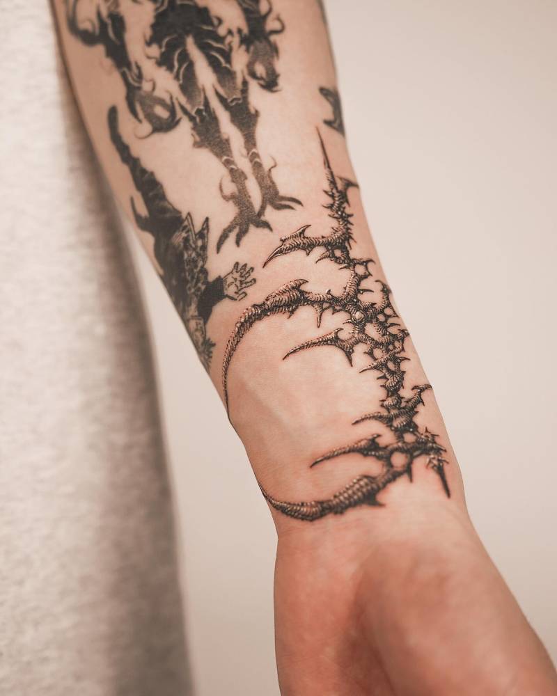 Crescent moon thorns tattoo located on the wrist, illustrative style.