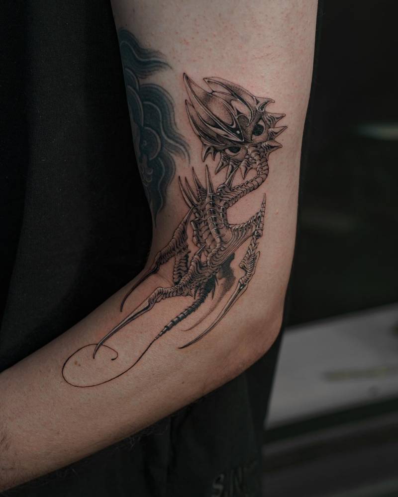 Dragon tattoo in cartoon style located on the arm.