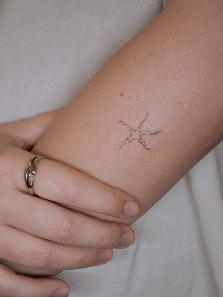 Fine line style star fish tattoo placed on the forearm.