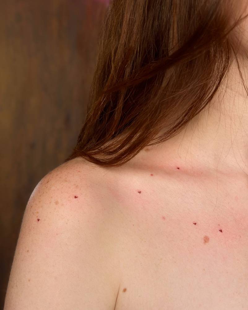 Heart freckles tattoo in minimalistic style located on the shoulder and collarbone.