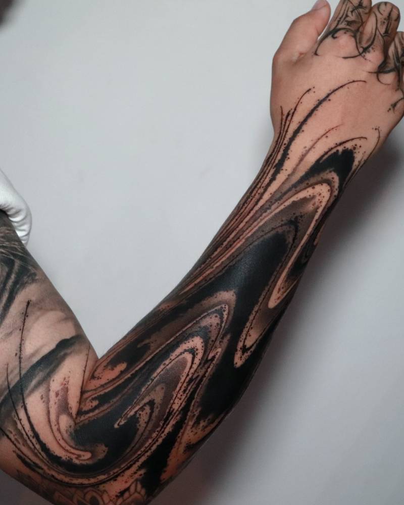 Abstract flow tattoo located on the forearm, blackwork style.