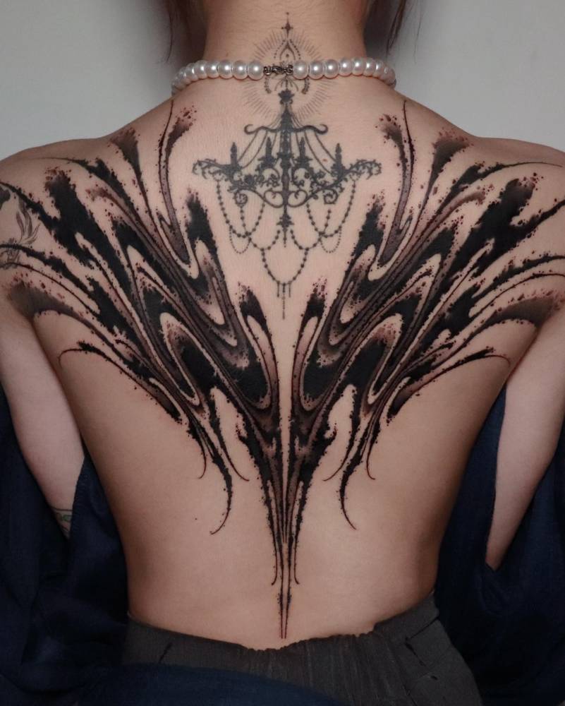 Abstract flow backpiece tattoo in blackwork style.