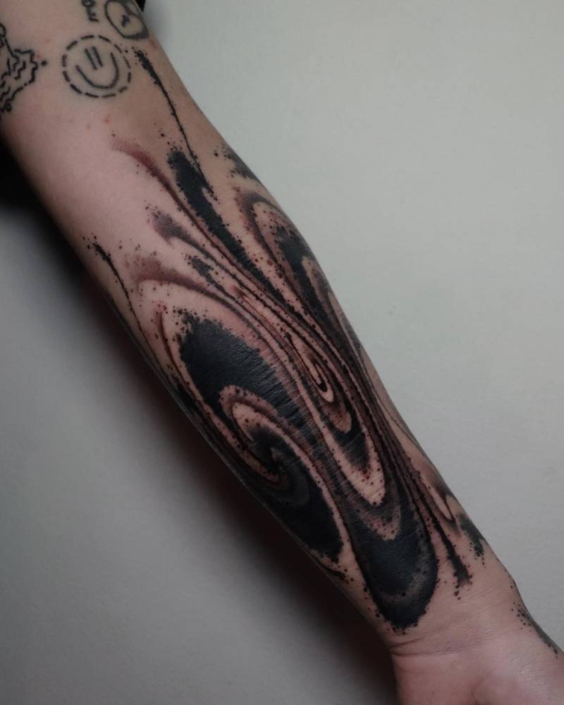 Abstract flow tattoo in blackwork style done on the inner forearm.