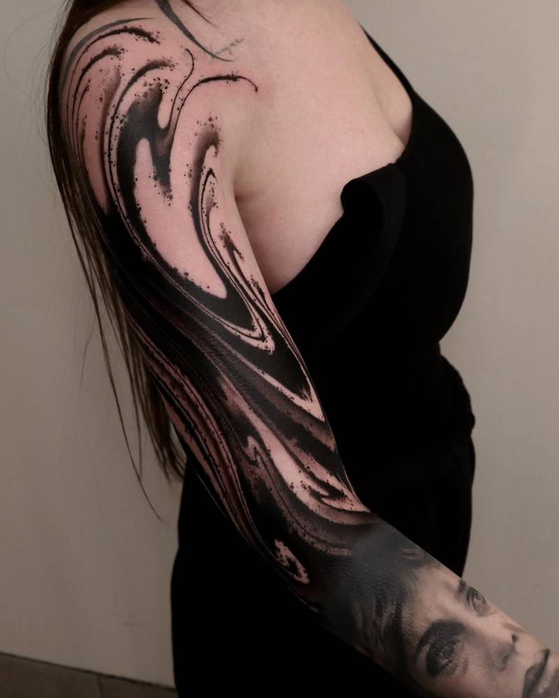 Abstract flow tattoo in blackwork style located on the upper arm.