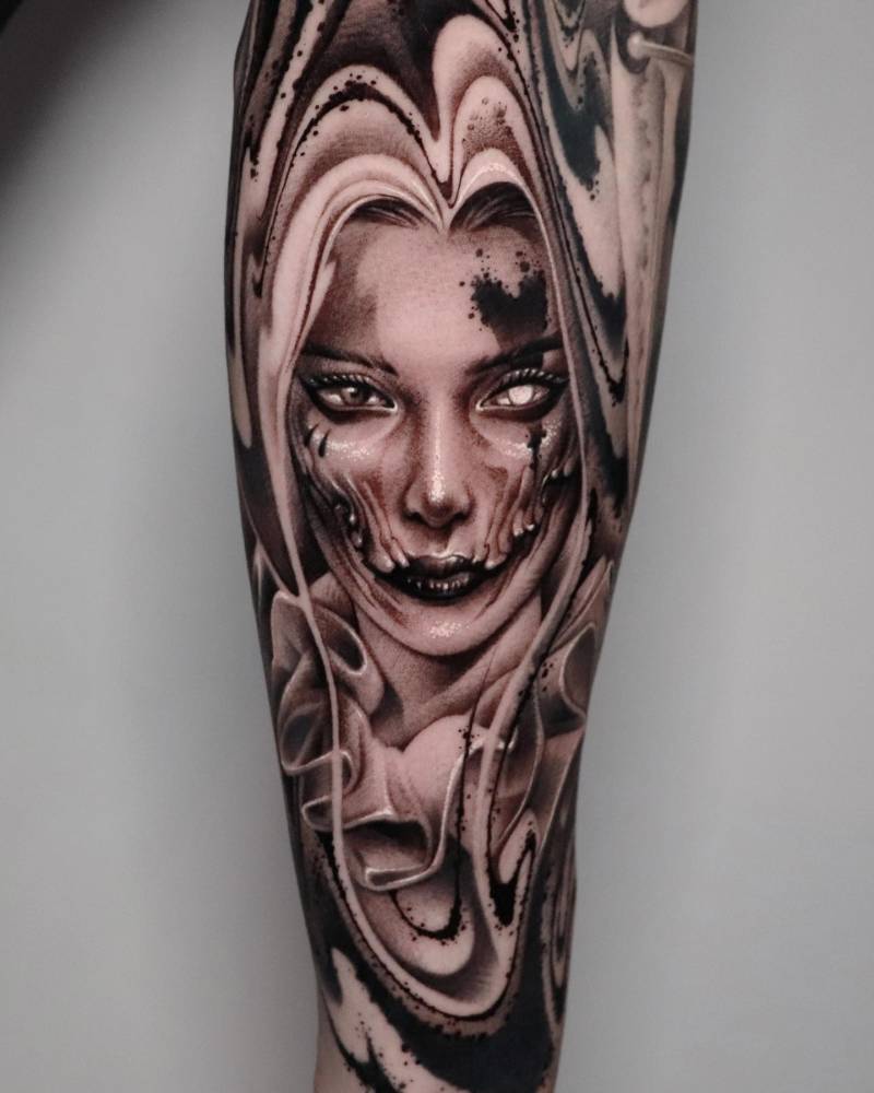 Harley Quinn portrait tattoo in black and grey style located on the inner forearm.