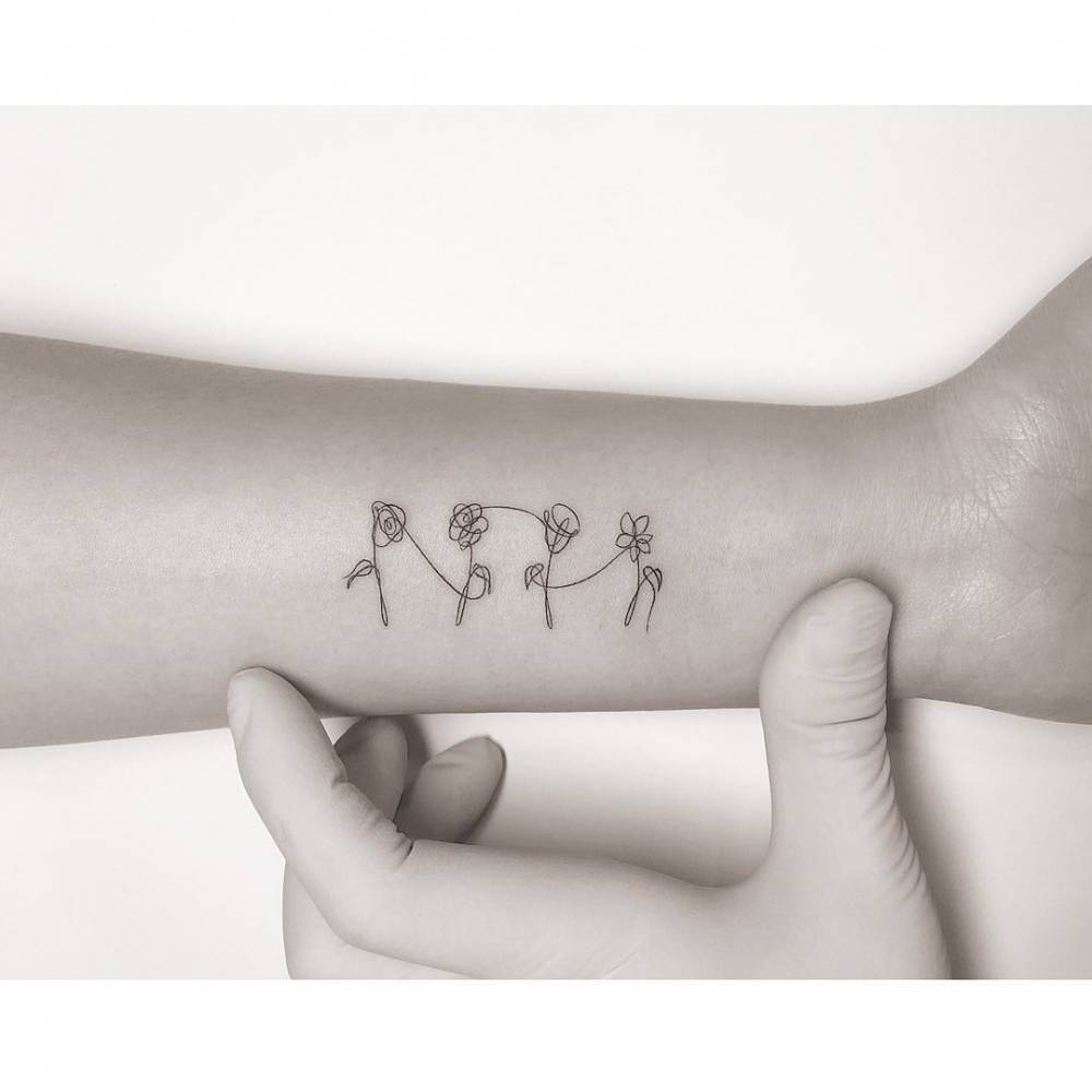 Continuous line flowers tattoo located on the wrist.