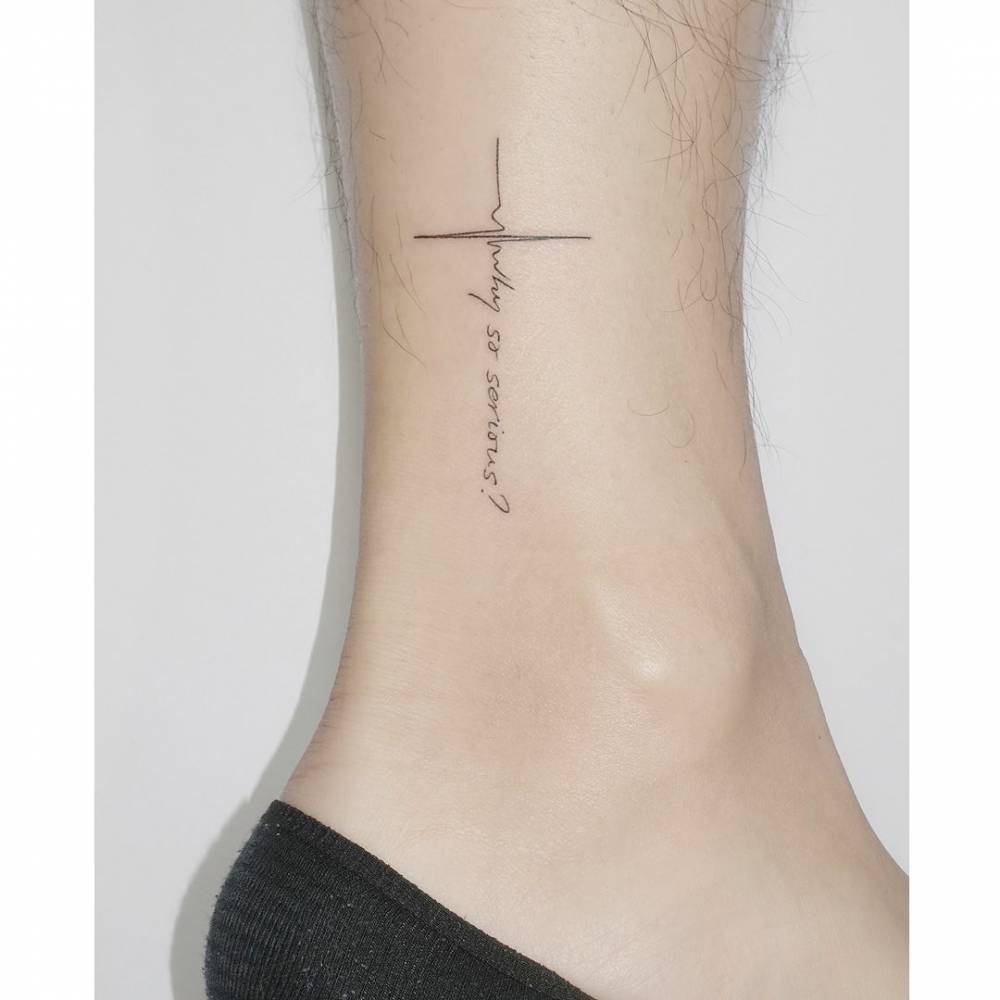 "Why so serious" lettering heartbeat cross tattoo located on the ankle.