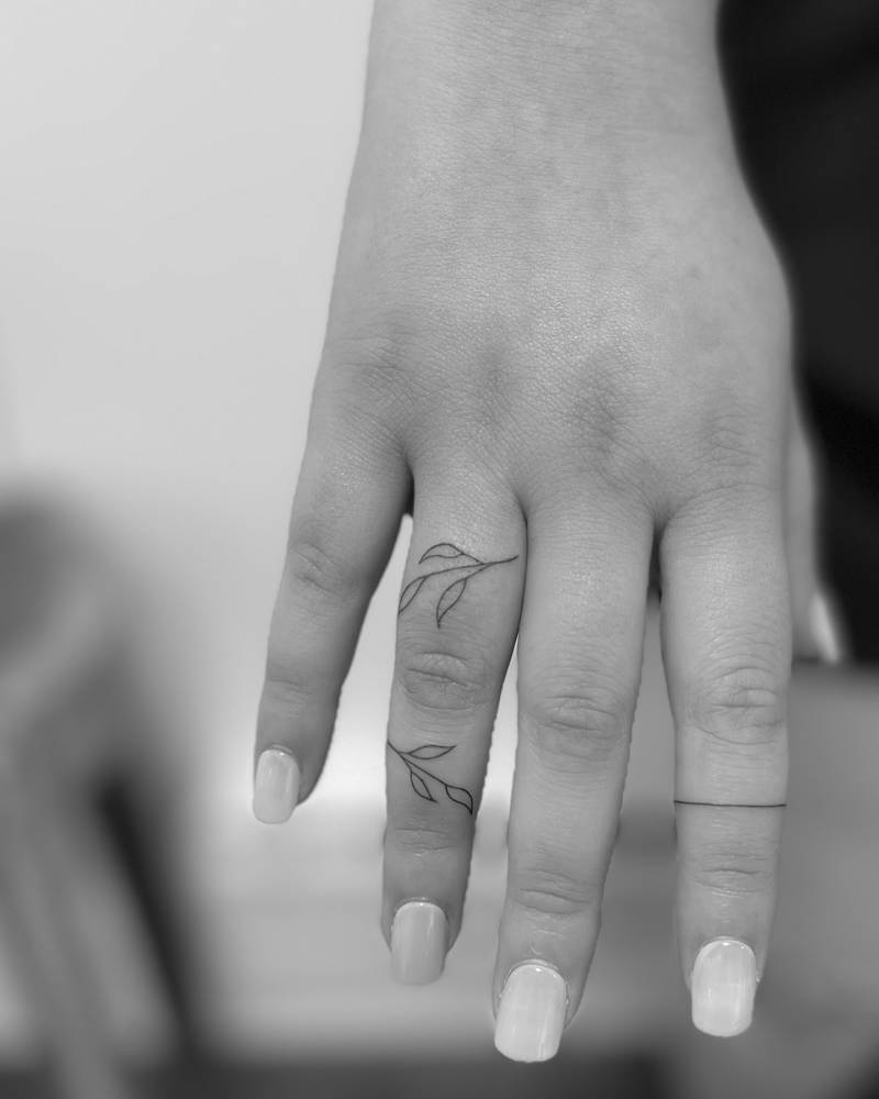 Fine line style leaves tattoo located on the finger.