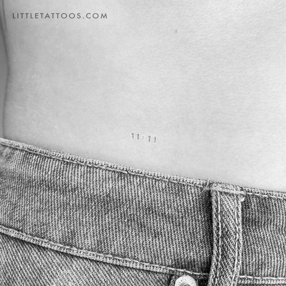 Tiny angel number "11:11" temporary tattoo located on the lower back.