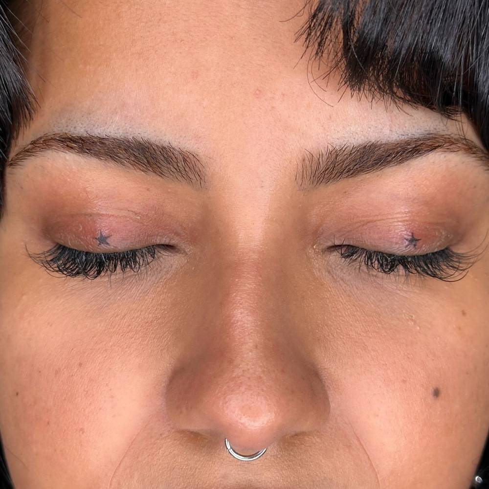 Hand poked minimalistic stars tattooed on the eyelids.