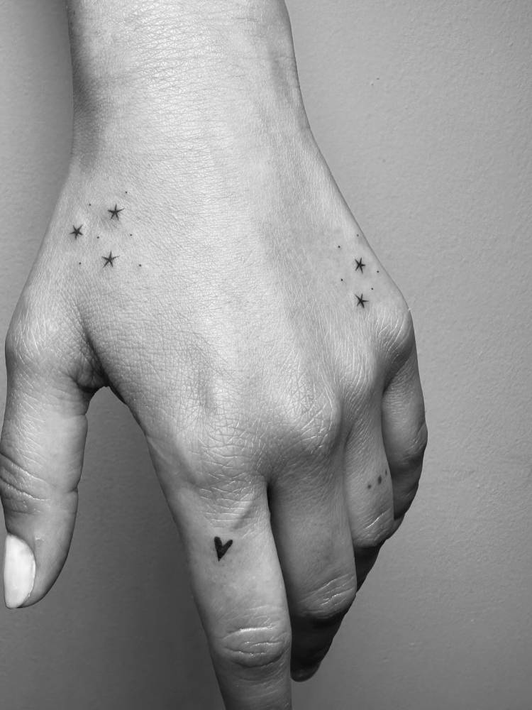 Stars and heart tattoos located on the hand, minimalistic style.