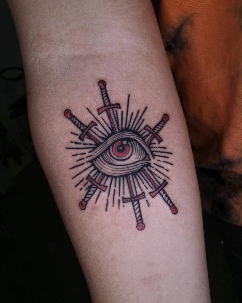 Eye and swords tattoo in engraving style placed on the inner forearm.