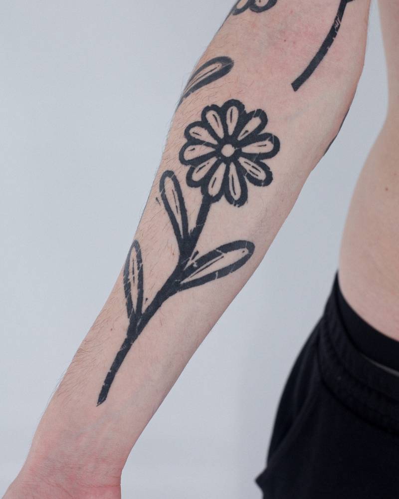 Daisy flower tattoo in blackwork style placed on the inner forearm.