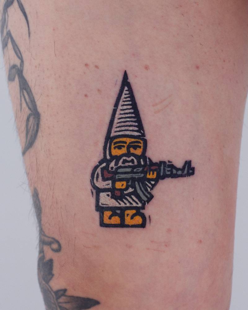 Gnome and Ak47 tattoo located on the thigh, pop art style.