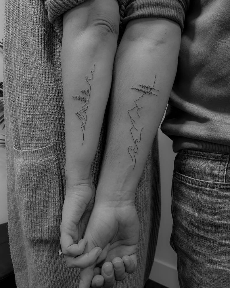 Matching mountain landscape tattoo for couple.