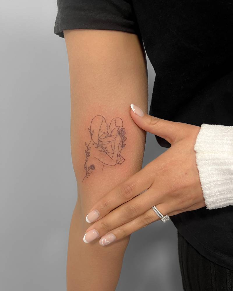 Motherhood tattoo in fine line style located on the inner forearm.