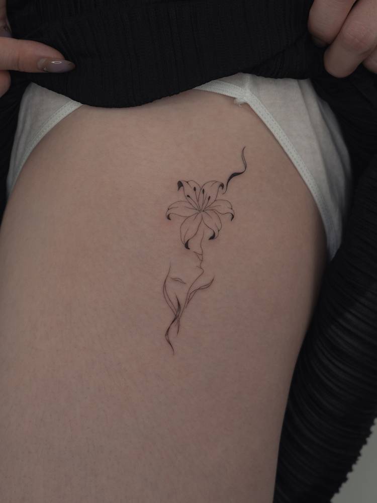 Single needle flower head woman tattoo located on the thigh.