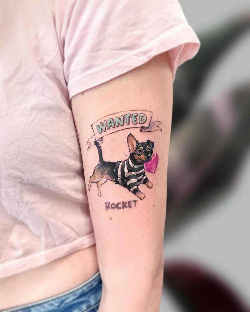 Watercolor style dog tattoo located on the upper arm.