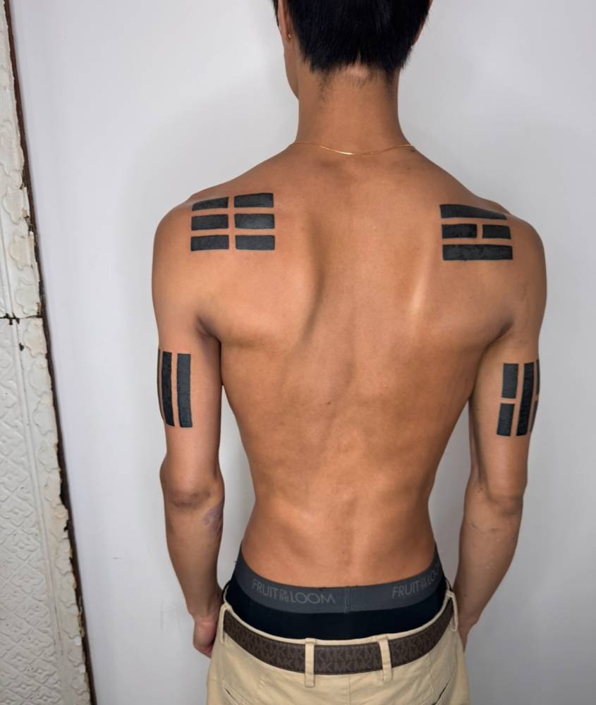 Blackwork style geometric tattoos located on the shoulder blades and triceps.