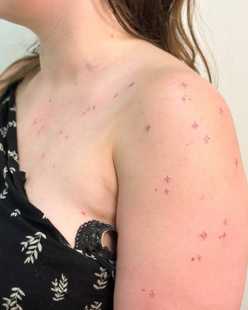 Tiny stars collection tattooed on the shoulder, done in fine line style.