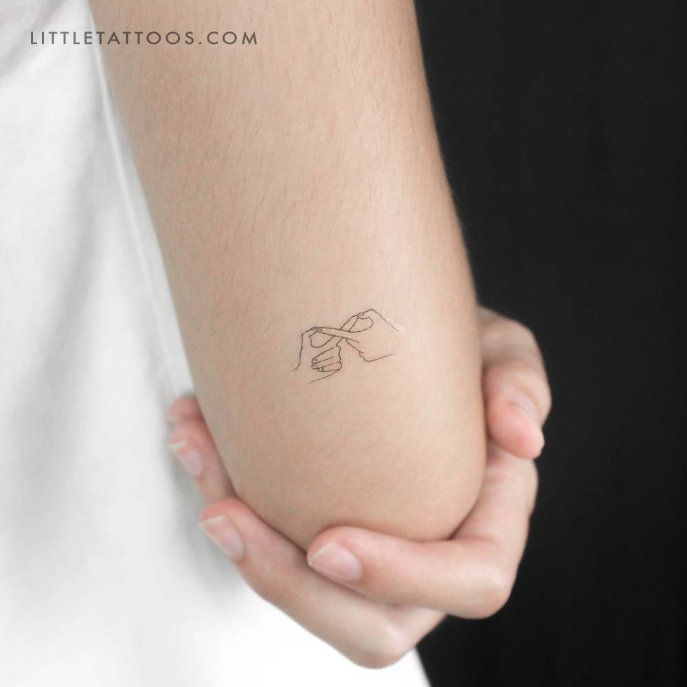 Fine line style infinity hand gesture temporary tattoo located on the tricep.