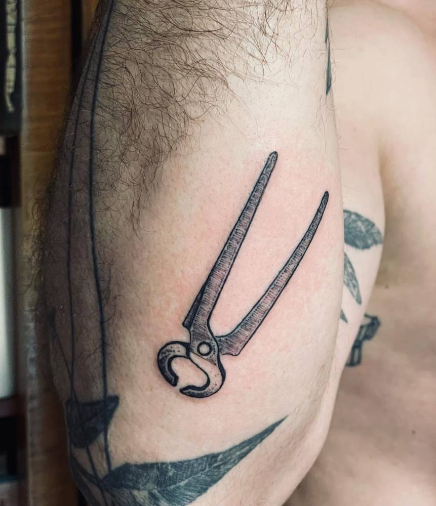 Engraving style pincer tattoo located on the forearm.
