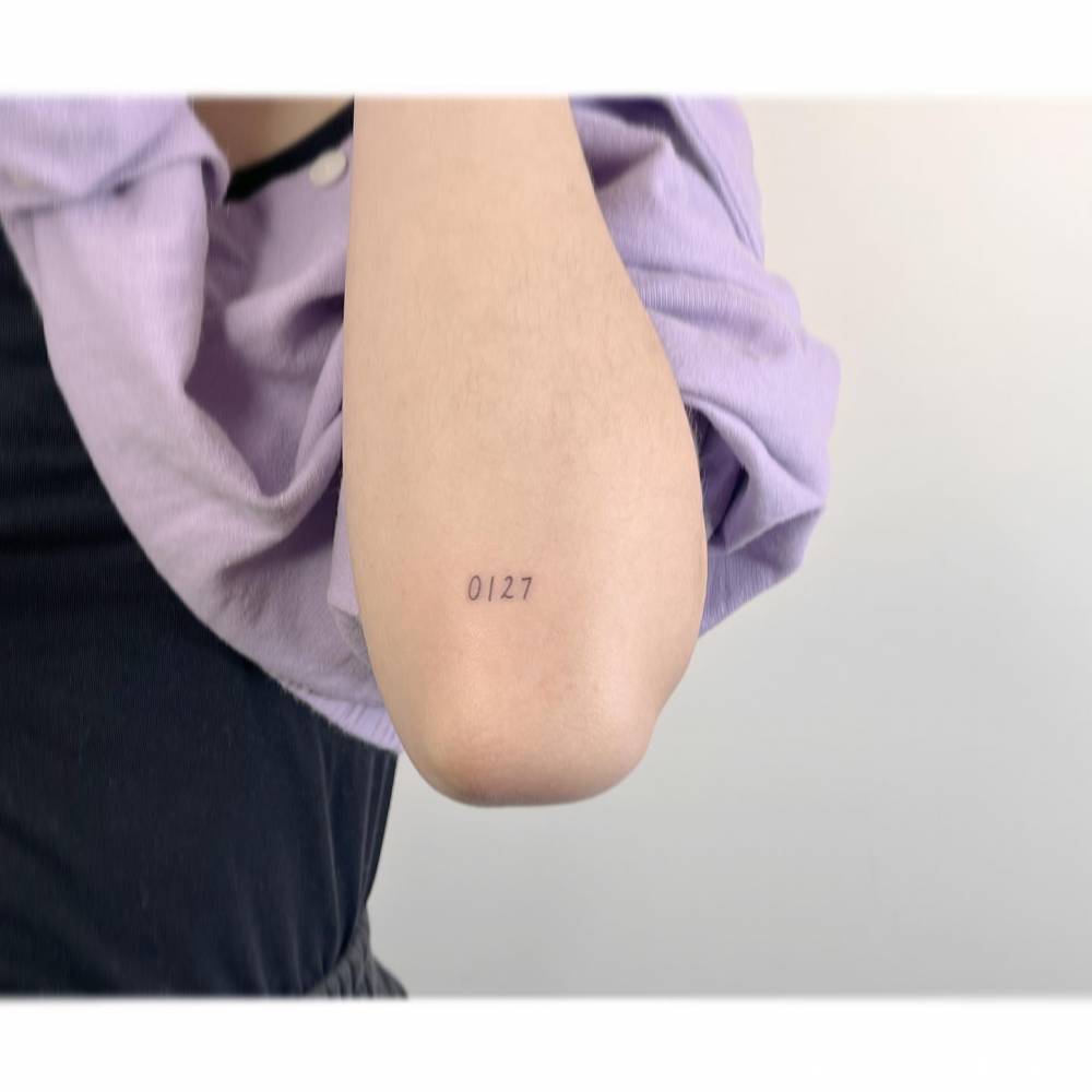 Number "0127" tattoo located on the elbow.