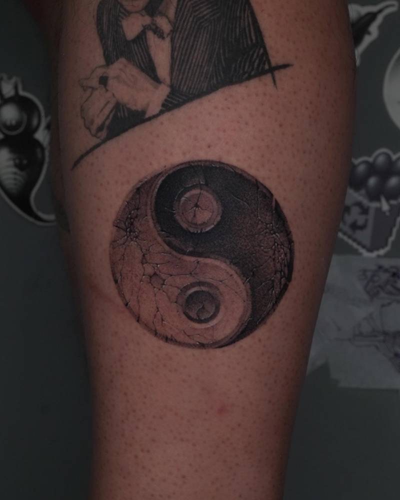 Yin Yang tattoo in black and grey style located on the calf.