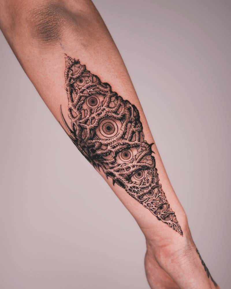 Illustrative style eyes and thorns tattoo placed on the forearm.