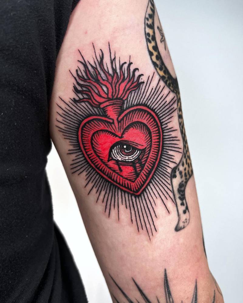 Engraving style crying flaming heart tattoo located on the tricep.