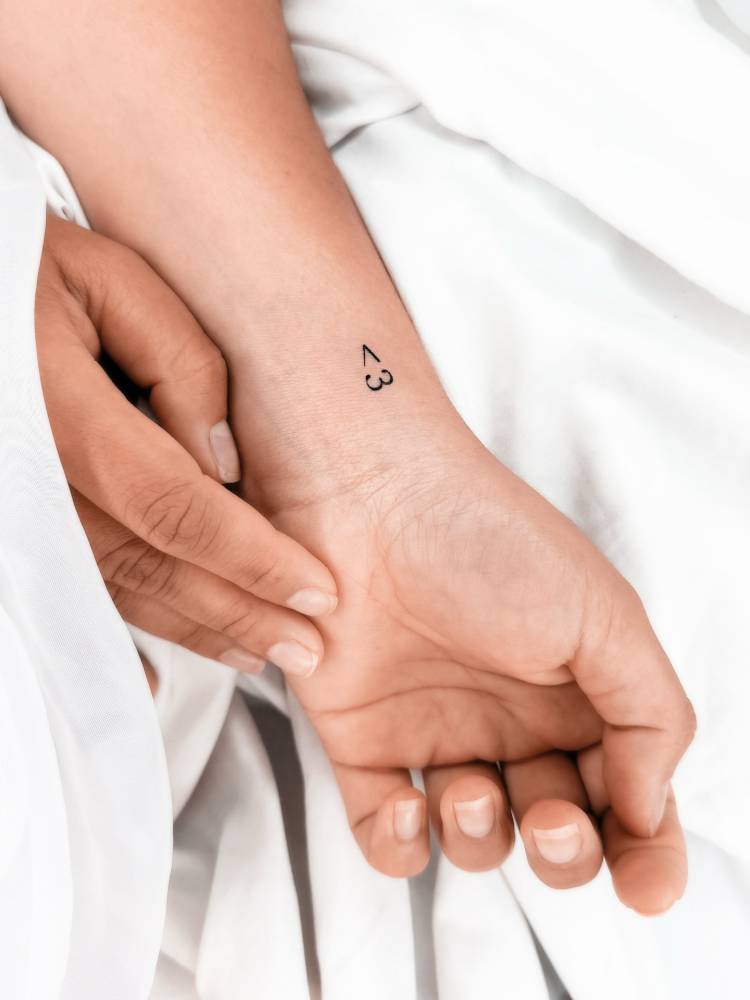Heart emoticon tattoo in minimalistic style located on the wrist.