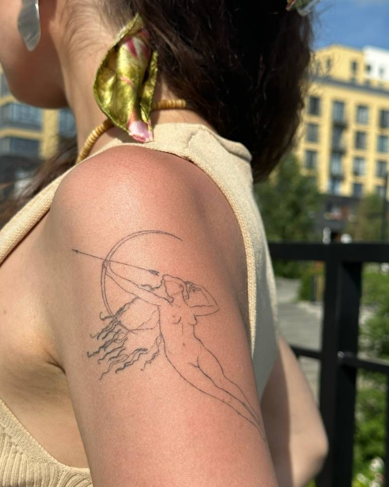 Healed nude archer tattoo in fine line style located on the upper arm.
