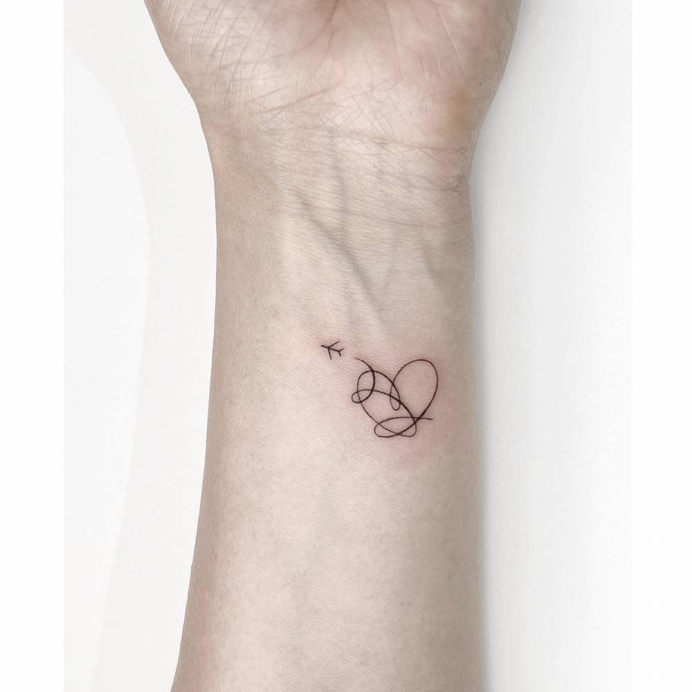 BTS heart and airplane tattoo located on the wrist.