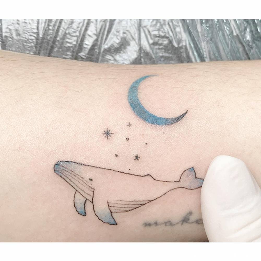 Whale, moon and stars tattoo located on the inner arm.