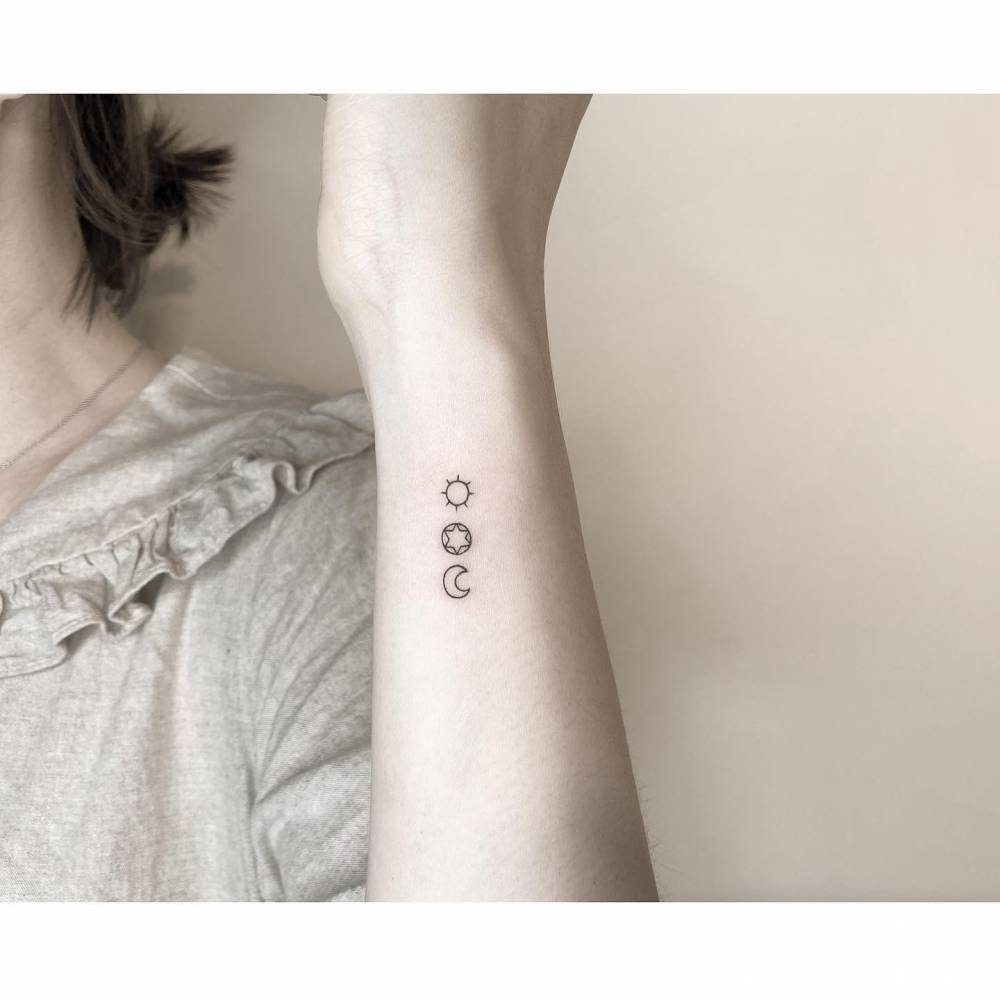 Sun, star and moon tattoo in minimalistic style placed on the wrist.