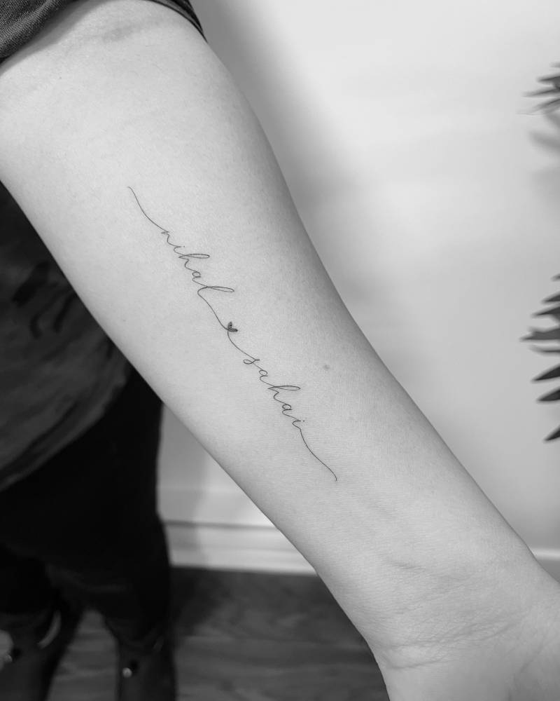 Handwritten font names tattoo located on the inner forearm.