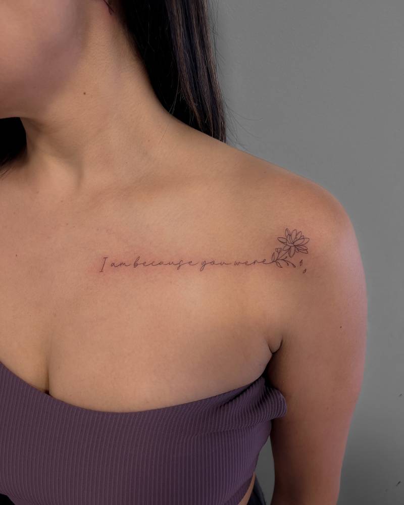 "I am because you were" and lotus flower tattoo located on the chest and shoulder.