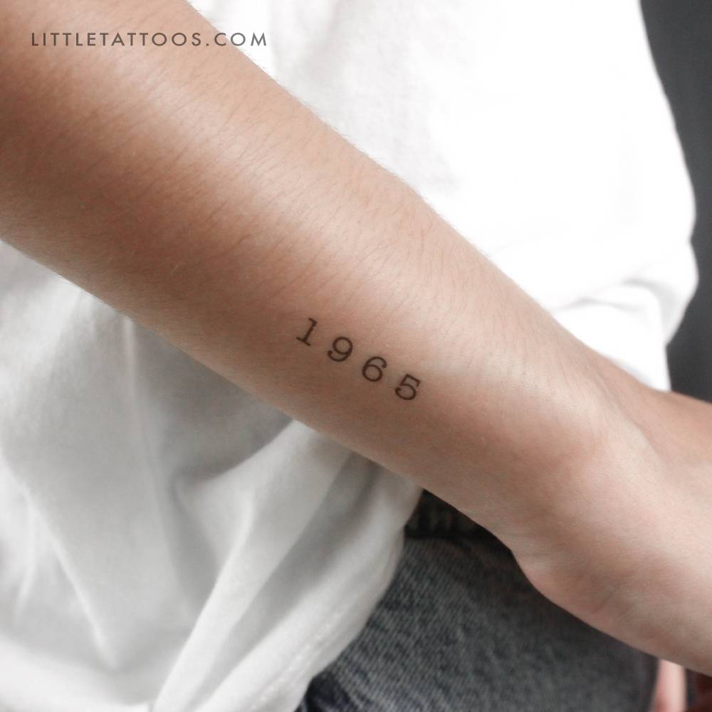 Typewriter font "1965" birth year temporary tattoo located on the wrist.